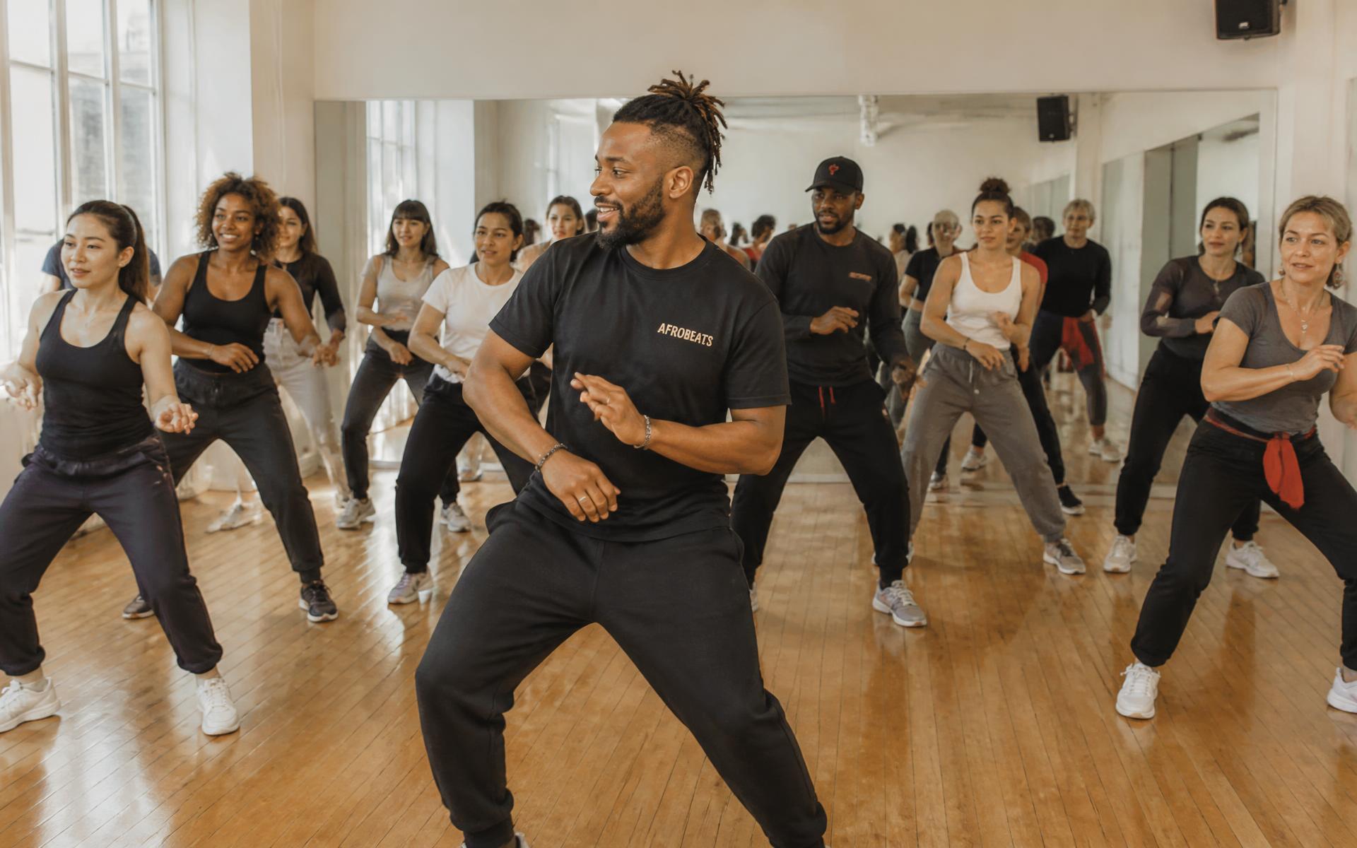 Adults following an instructor in a beginner afrobeats class